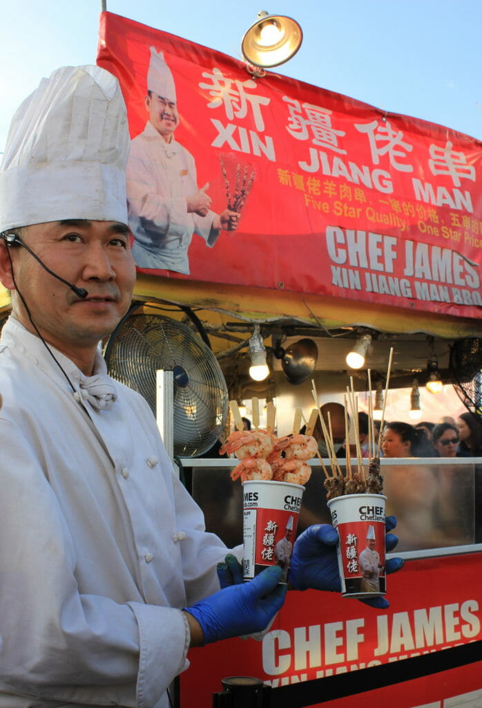 image of Chef James holding up his lamb, beef, and chicken skewers