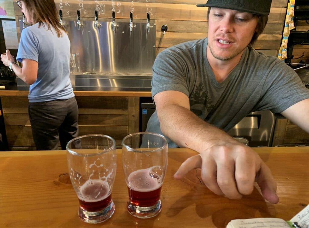 Brent Malysh, owner of Backroads Brewing in Nelson, BC, explaining what beers are being tasted in two flight glasses