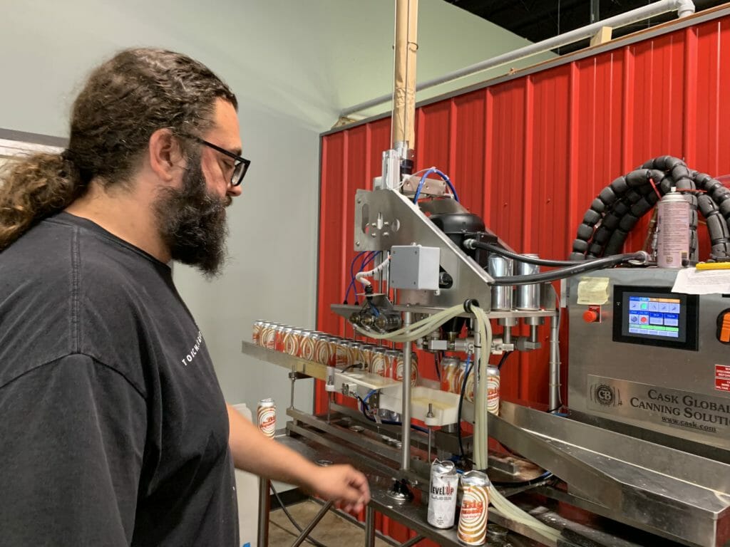 image of Craig Swendson, owner of Torchlight Brewing in Nelson, BC, operating packaging line