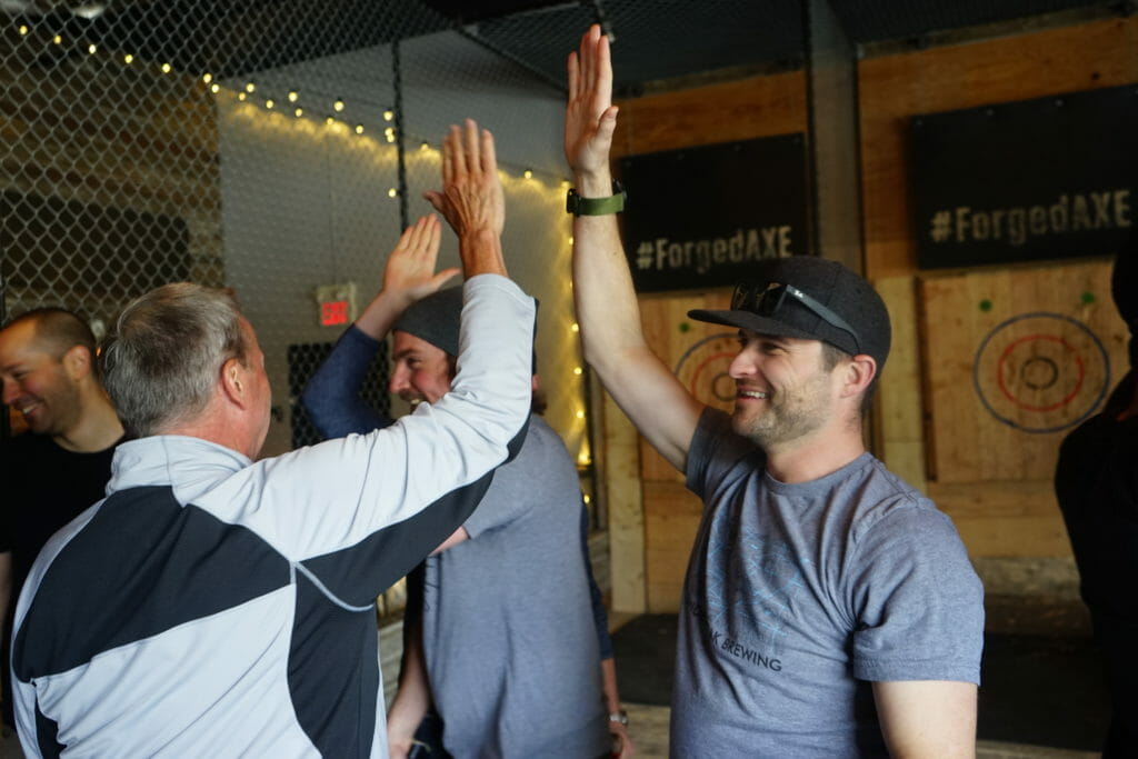 a few men high-fiving at Forged Axe Throwing in Whistler, BC