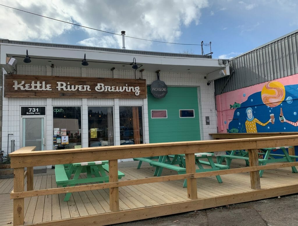 image of Kettle River Brewing's tasting room front, with Provisions Kitchen sign hanging next to it above the patio area