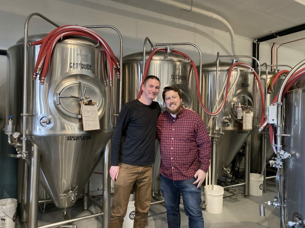 photo of Aaron Johnson, host of podcast with Aaron Colyn, owner of Twin City Brewing in Port Alberni standing in front of brewtanks