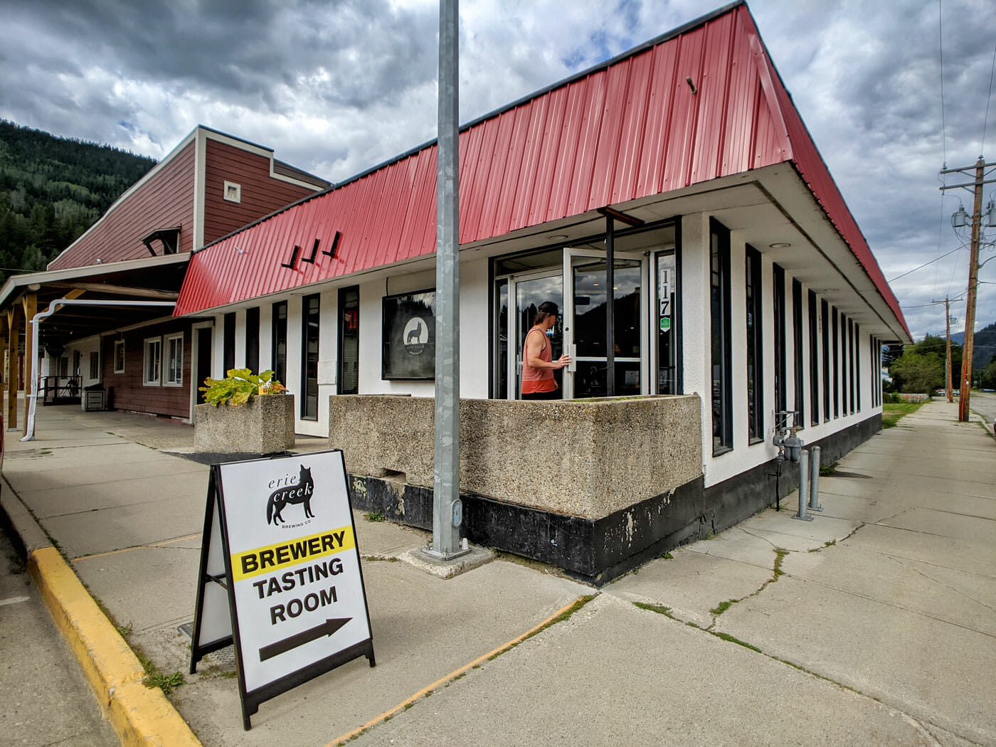 Man entering West Kootenay brewery, Erie Creek, with tasting room sign on sidewalk