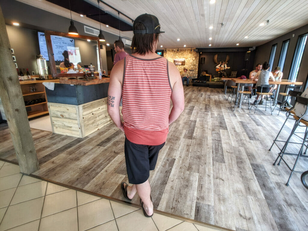 Man stands in line at a West Kootenay brewery with performer on stage in background