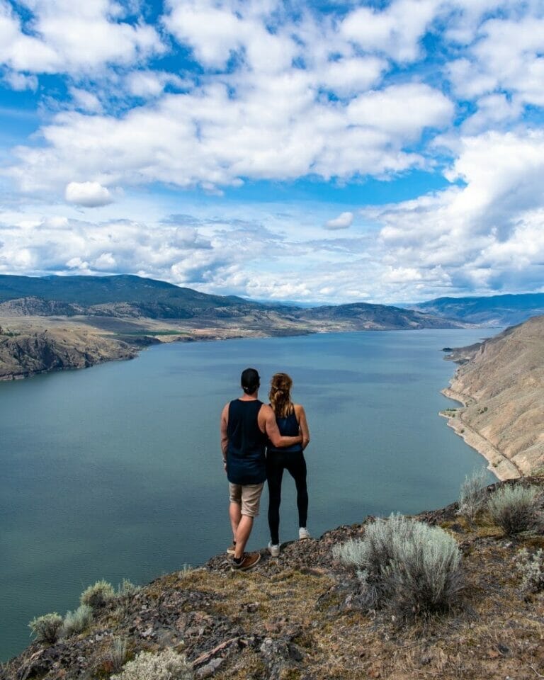 Photo of a couple standing on Battle Bluff overlooking Kamloops Lake.