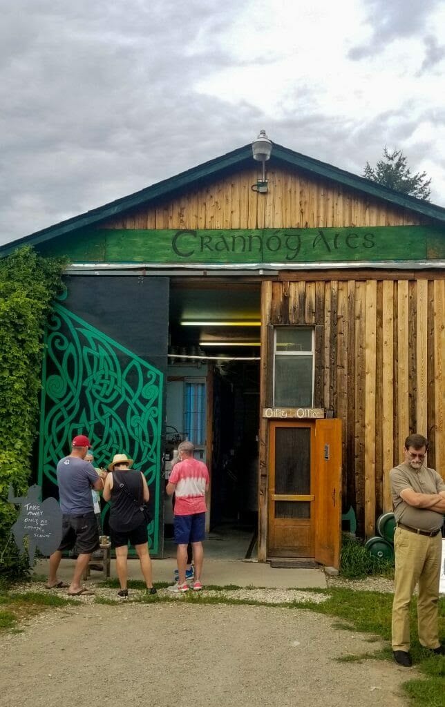 Photo of several people standing outside a wooden structure with Crannog Ales written at the top.