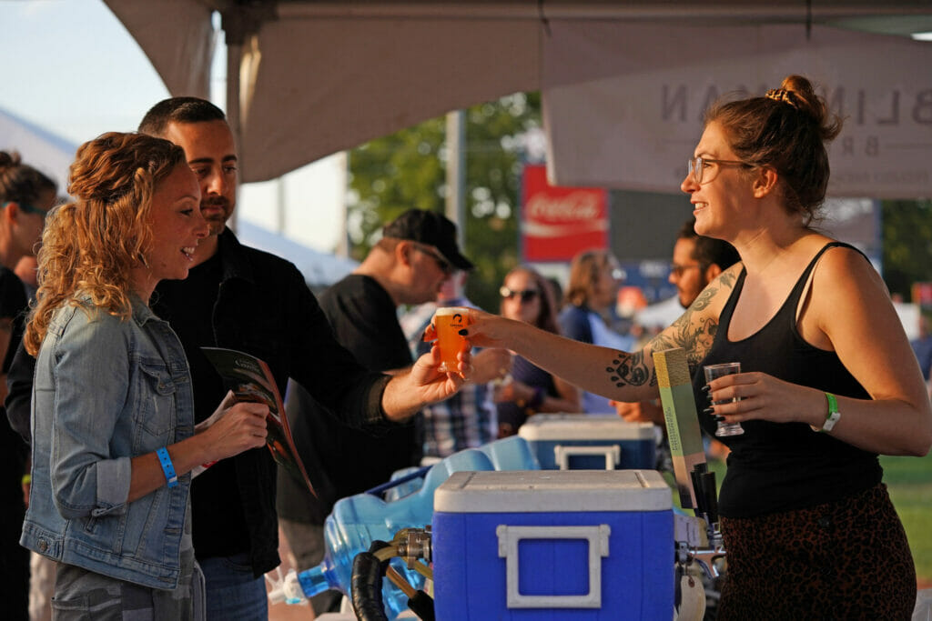 A staff member hands festival goers their beer sample at the Great Canadian Beer Festival