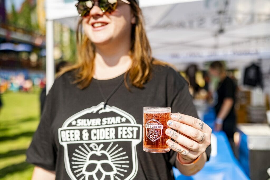 A staff member holding a full sample glass at the Silver Star Beer & Cider Fest