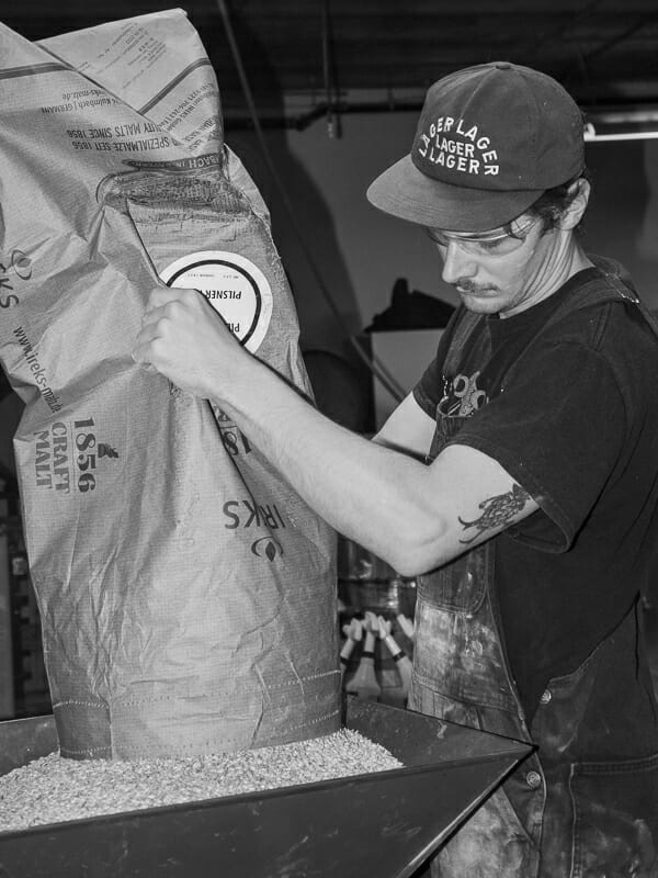 Connor Blanchard milling grains during mash-in at Luppolo Brewing