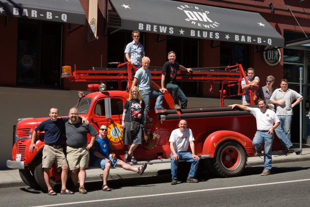 A group of brewers sitting and standing on a red fire truck outside of Dix BBQ and Brewhouse